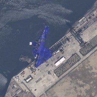【朝鲜新型驱逐舰下水事故】朝鲜新型5000吨级驱逐舰发生下水事故后被蓝色防水布遮挡。5月22日，朝中社报道朝鲜清津造船厂新驱逐舰出现下水事故，新舰艇在滑轨入水过程中发生侧翻。朝鲜最高领导人金正恩目睹事故全过程并对此进行严厉批评，要求尽快修复驱逐舰并对事故立案审查。初步调查报告显示该舰体受损程度不严重，主要受损为右舷刮削和船尾进水，并未出现船底破洞，预计抽水和修复工作需要耗费10余天时间。 source